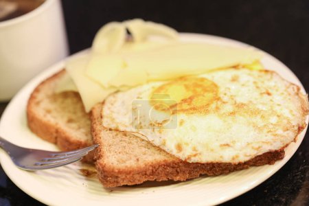 Foto de Vista de cerca de tostadas con mantequilla y huevos fritos y taza de té en la mesa - Imagen libre de derechos