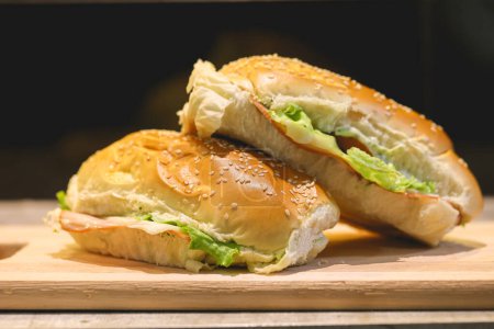 Foto de Sandwiches de pan con semillas de sésamo, pechuga de pavo, queso mozzarella, lechuga, tomates y mayonesa sazonada - Imagen libre de derechos