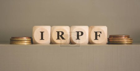 Foto de El acrónimo IRPF está escrito en cubos y monedas de madera sobre fondo gris. Estudio foto. - Imagen libre de derechos