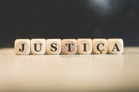 Photo for The word JUSTICE in Brazilian Portuguese written on wooden cubes. Black background. - Royalty Free Image