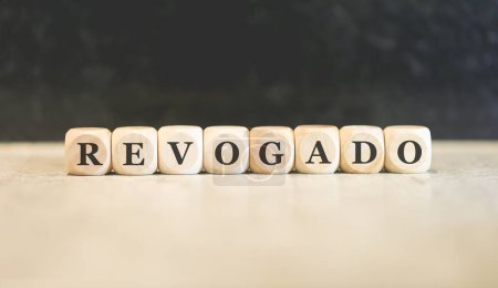Photo for The word revoked in Brazilian Portuguese written on wooden cubes. Black background. - Royalty Free Image