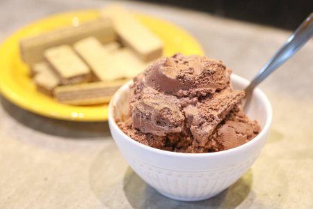 Photo for Chocolate ice cream in a white bowl and wafer cookies with chocolate in the composition. Close-up photo. - Royalty Free Image
