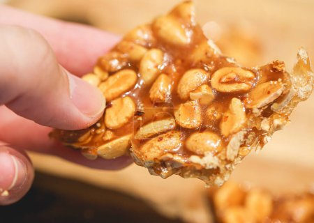 Photo for Close-up of person holding sweet peanut brittle - Royalty Free Image