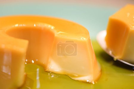 Photo for A small custard pudding served on a green dessert plate. Brazilian dessert in Portuguese called: Pudim de leite condensado. - Royalty Free Image