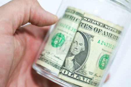Téléchargez les photos : Bons du dollar américain sur une table en bois avec un bocal en verre en macro photographie. Concept d'économie. - en image libre de droit