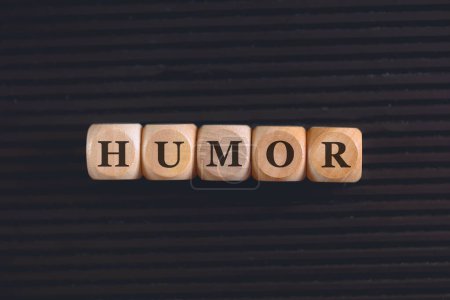 Foto de La palabra humor escrita en bloques de madera sobre fondo negro. Primer plano foto. - Imagen libre de derechos