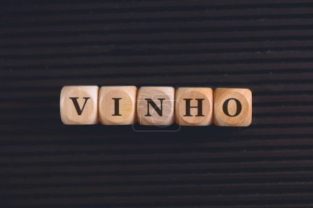Foto de Inscripción VINO en portugués brasileño escrito en cubos de madera. Fondo negro. - Imagen libre de derechos