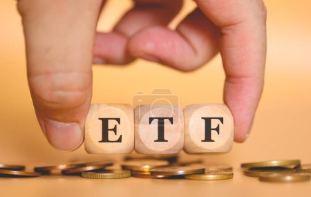 Close-up view of man forming acronym ETF written on wooden cubes. Studio photo. 