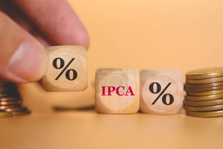 Foto de Vista de cerca del hombre formando el símbolo porcentual y el acrónimo IPCA escrito en cubos de madera. Estudio foto. - Imagen libre de derechos