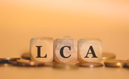 Photo for Acronym LCA for Agribusiness Letter of Credit in Brazilian Portuguese written on wooden cubes and piles of coins. Studio photo. - Royalty Free Image