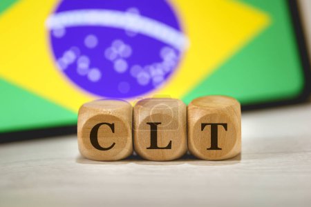 Téléchargez les photos : L'acronyme CLT pour Consolidation of Labor Laws in Brazil écrit sur des cubes de bois. Un téléphone portable avec le drapeau brésilien à l'écran dans la composition. - en image libre de droit