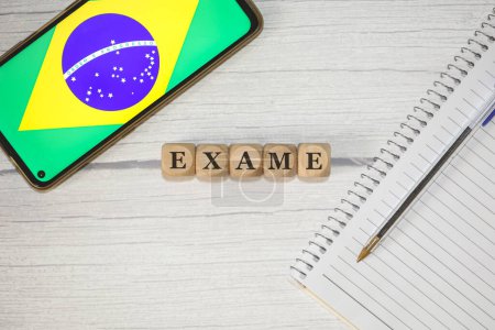 Photo for The text EXAM in Portuguese written on wooden cubes on a wooden table. A notebook, a pen and a cell phone with the Brazilian flag in the composition. - Royalty Free Image