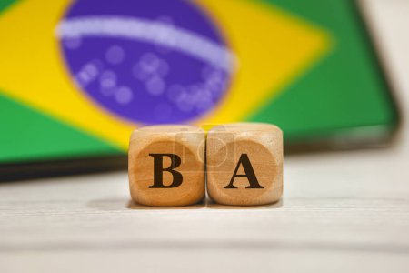 Téléchargez les photos : L'acronyme BA écrit sur des cubes en bois. Un téléphone portable avec le drapeau brésilien à l'écran dans la composition. - en image libre de droit