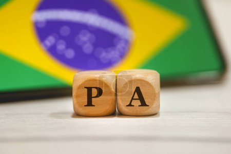 Photo for The acronym PA written on wooden cubes. A cell phone with the Brazilian flag on the screen in the composition. - Royalty Free Image
