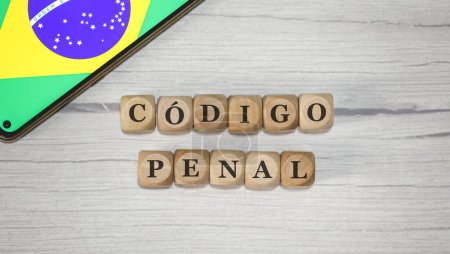 Téléchargez les photos : Le texte CODE CRIMINEL en portugais brésilien écrit sur des cubes de bois. Un téléphone portable avec le drapeau brésilien affiché à l'écran dans la composition. - en image libre de droit