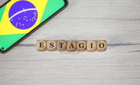 Photo for The text INTERNSHIP in Brazilian Portuguese written on wooden cubes. A cell phone with the Brazilian flag being shown on the screen in the composition. - Royalty Free Image