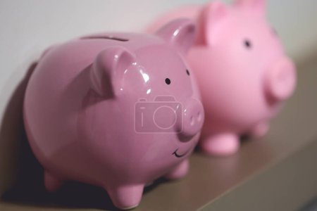 Photo for Close-up view of two piggy banks on piece of furniture. Finance concept. - Royalty Free Image