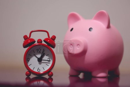 Photo for Close-up view of piggy bank and an alarm clock. Finance and time concepts. - Royalty Free Image