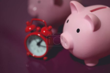 Photo for Close-up view of two piggy banks and alarm clock. Finance and time concepts. - Royalty Free Image