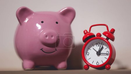 Photo for Close-up view of piggy bank and an alarm clock. Finance and time concepts. - Royalty Free Image