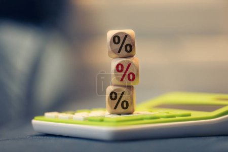 Foto de Porcentaje de símbolo escrito en cubos de madera. Una calculadora en la composición. - Imagen libre de derechos