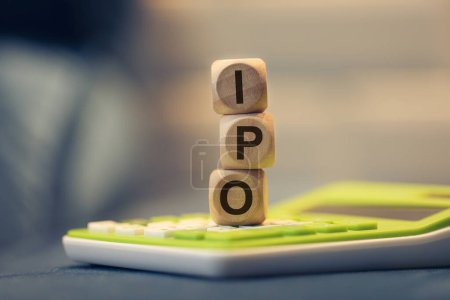 Das Akronym IPO für Initial Public Offering, geschrieben auf Holzwürfel. Ein Taschenrechner in der Zusammensetzung. 