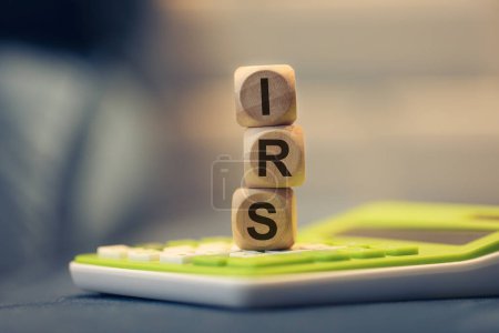 Foto de El acrónimo IRS escrito en cubos de madera. Una calculadora en la composición. - Imagen libre de derechos