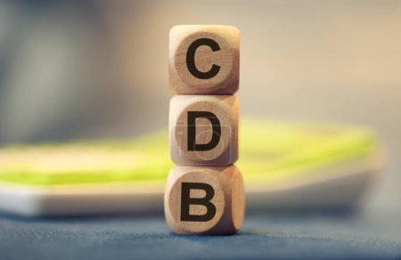 Téléchargez les photos : L'acronyme CDB pour Bank Deposit Certificate en portugais brésilien écrit sur des cubes en bois. Une calculatrice dans la composition. - en image libre de droit