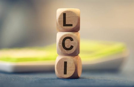 Téléchargez les photos : L'acronyme LCI écrit sur des cubes de bois. Une calculatrice dans la composition. - en image libre de droit