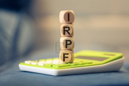 Photo for The acronym IRPF written on wooden cubes. A calculator in the composition. - Royalty Free Image