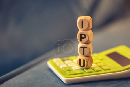 Photo for The acronym IPTU written on wooden cubes. A calculator in the composition. - Royalty Free Image