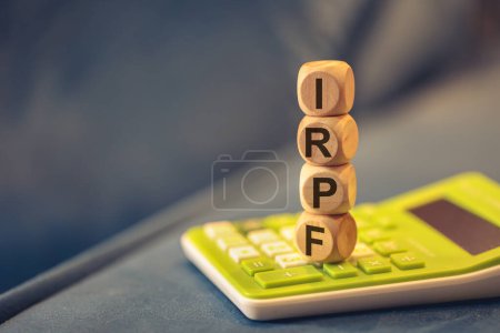 Téléchargez les photos : L'acronyme IRPF écrit sur des cubes de bois. Une calculatrice dans la composition. - en image libre de droit