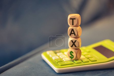 Photo for Word TAX written on wooden cubes. A calculator in the composition. Close-up - Royalty Free Image