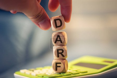 Photo for Close-up view of man forming acronym DARF with wooden cubes. A calculator in the composition. - Royalty Free Image
