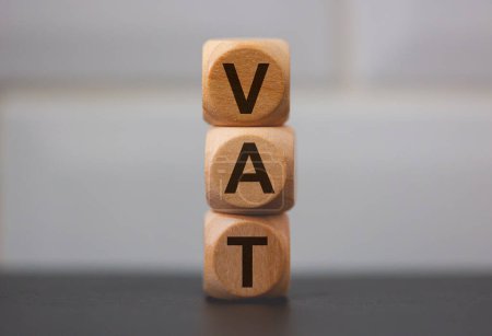 Téléchargez les photos : L'acronyme TVA pour la taxe sur la valeur ajoutée inscrit sur des cubes de bois sur fond gris - en image libre de droit