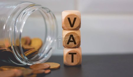 Foto de Acrónimo IVA para el Impuesto sobre el Valor Añadido escrito sobre cubos de madera y pilas de monedas. Estudio foto. - Imagen libre de derechos