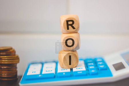Foto de El acrónimo ROI está escrito en cubos de madera. Una calculadora en la composición. - Imagen libre de derechos