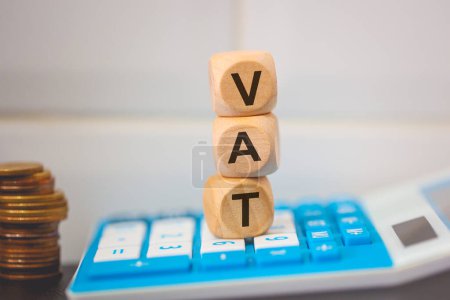 Photo for The acronym VAT written on wooden cubes. A calculator in the composition. - Royalty Free Image