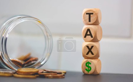 Photo for Word TAX written on wooden cubes and piles of coins. Studio photo. - Royalty Free Image