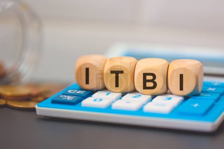 Foto de El acrónimo ITBI escrito en cubos de madera. Una calculadora en la composición. - Imagen libre de derechos
