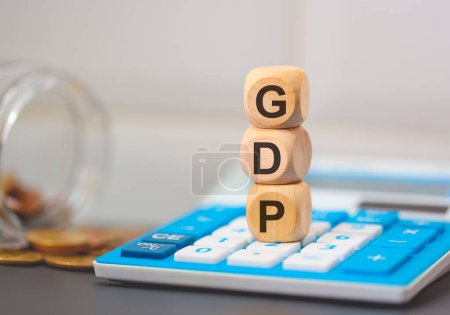 Téléchargez les photos : L'acronyme GDP écrit sur des cubes de bois. Une calculatrice dans la composition. - en image libre de droit