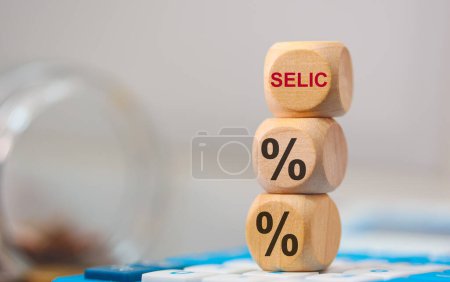 Prozentsatz-Symbol und das Akronym SELIC auf Holzwürfeln. Ein Taschenrechner in der Zusammensetzung. 