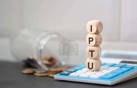 Foto de El acrónimo IPTU escrito en cubos de madera. Una calculadora en la composición. - Imagen libre de derechos