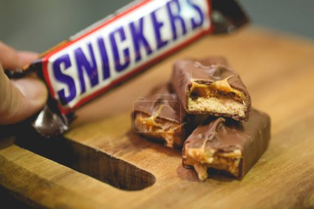 Téléchargez les photos : Vue rapprochée des barres de chocolat Snickers sur fond en bois - en image libre de droit