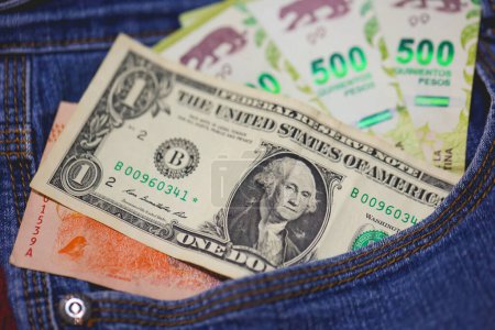Foto de Billetes de peso argentino y billetes de dólar de los Estados Unidos en un bolsillo vaquero en macro foto. - Imagen libre de derechos