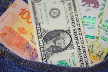 Foto de Billetes de peso argentino y billetes de dólar de los Estados Unidos en un bolsillo vaquero en macro foto. - Imagen libre de derechos