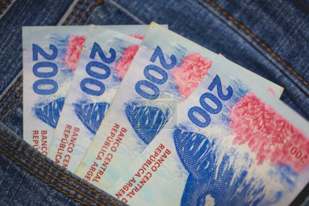 Argentine peso banknotes in a jeans pocket in macro photo.