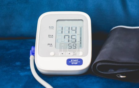 Foto de Monitor electrónico de presión arterial sobre fondo de sofá azul - Imagen libre de derechos
