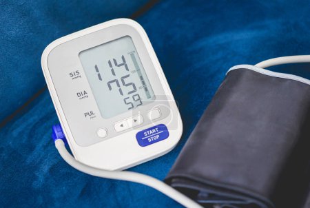 Foto de Monitor electrónico de presión arterial sobre fondo de sofá azul - Imagen libre de derechos