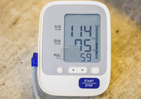 Foto de Monitor electrónico de presión arterial sobre fondo de mesa de madera - Imagen libre de derechos